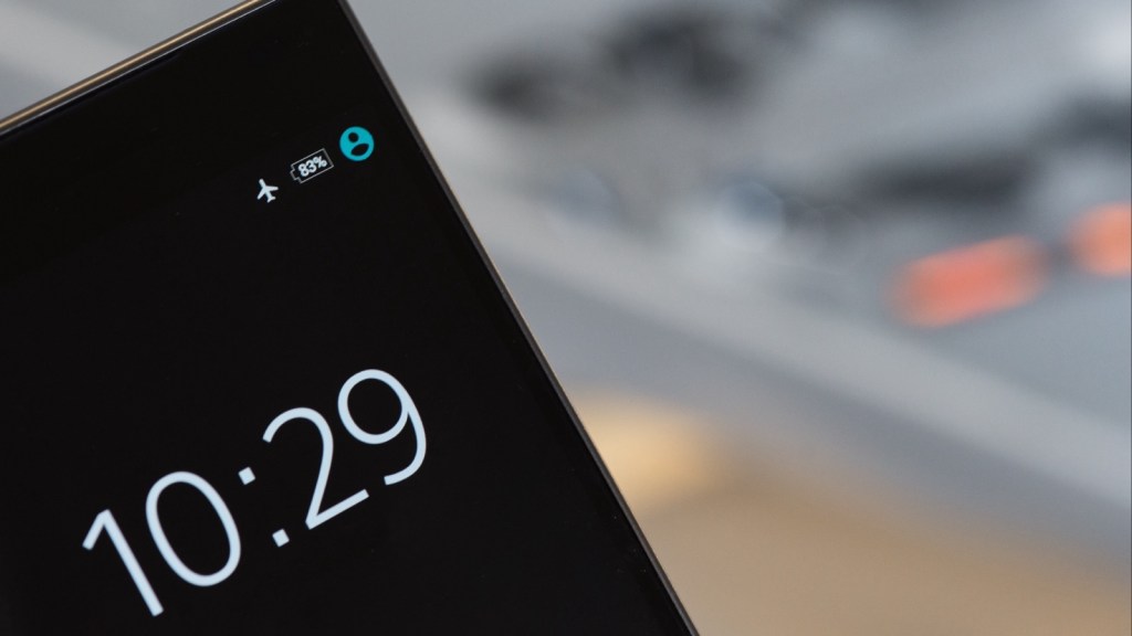 Close-up of a black smartphone lock screen showing the time 10:29 and an 83% battery icon, against a softly blurred grey background